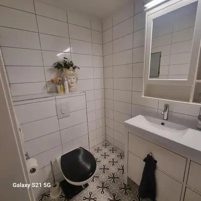 a bathroom with a black toilet and a sink at Quiet home with garden in Bergen