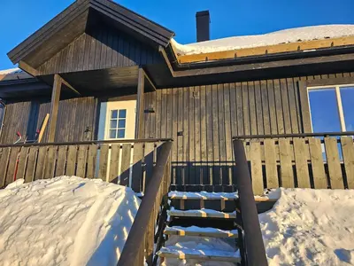 a house with a wooden fence and a wooden ramp in the snow at Flott hytte i Elgtrakket 9, 3864 Rauland Skisenter - Holtardalen in Torvetjørn