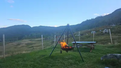 a picnic table and a camp fire in a field at Authentic Secluded Mountain Cabin in Telemark with Panoramic Views