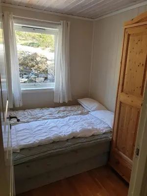 a small bed in a room with a window at Spacious Wood Cabin 50 min from Bergen in Eikedalen