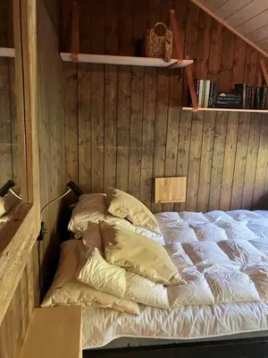 a bed with pillows in a room with wooden walls at Ski in ski out in Geilo, comfortable and family friendly cabin in Geilo