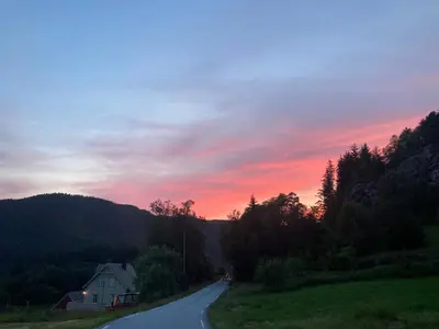 a house on a road with a sunset in the background at West coast peace in Hyllestad