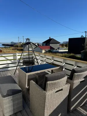 a patio with wicker chairs and a table on a deck at Et hus dypt i havet in Steinshamn