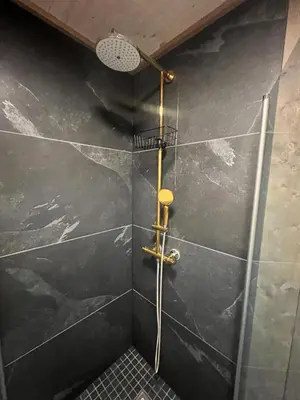 a shower in a bathroom with black tiles at Solsiden Geilo Cozy Studio location Geilo Centrum in Hol