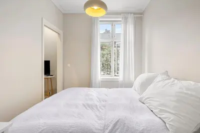 a white bedroom with a white bed and a window at Inviting & Cozy City Apartment in Bergen