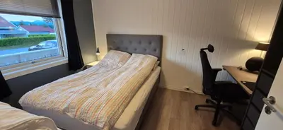 a bedroom with a bed and a desk and a window at Central Langevåg Family Apartment in Sula