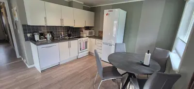 a kitchen with a table and a white refrigerator at Central Langevåg Family Apartment in Sula