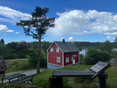 a red house with a picnic table and a bench at Haus Harald in Tysnes
