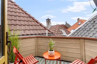 a balcony with a table and chairs and roofs at Historic Gem I Charming Bergen Home in Bergen