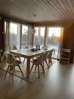a dining room table and chairs in a room with windows at Blefjell hytte med fantastisk utsikt in Kongsberg
