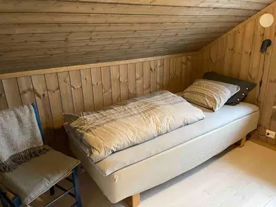 a bed in a wooden room with a chair at Blefjell hytte med fantastisk utsikt in Kongsberg