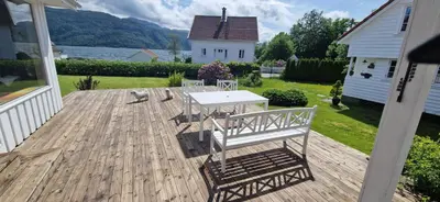 a patio with two chairs and a table on a deck at Hus ved sjøen, med strand og naust in Sauda