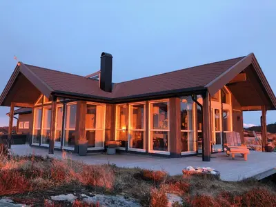 a large wooden house with glass windows and a bench at Drømmeplassen in Averoy