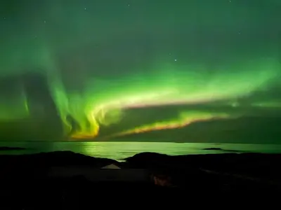 an aurora in the sky over a body of water at Drømmeplassen in Averoy