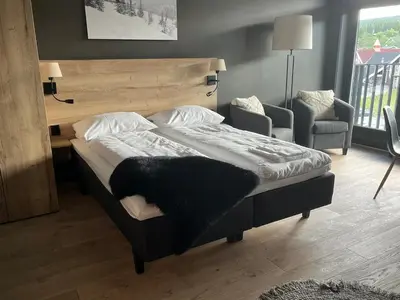 a large bed in a room with a chair and a bed sidx sidx at Trysil Alpine Lodge - 510 in Trysil