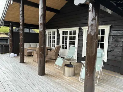 a wooden deck with chairs and a table on a house at Fjellhytte sentralt og solrikt in Stryn