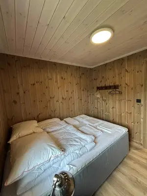 a large bed in a room with a wooden wall at Fjellhytte sentralt og solrikt in Stryn