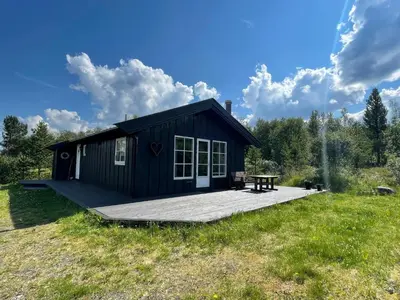 a black cabin with a picnic table in a field at Revehiet - 3 bedroom cabin in the center of Geilo in Geilo