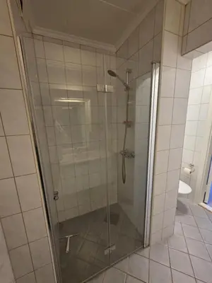 a shower with a glass door in a bathroom at Best flat in town in Kristiansund