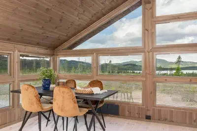 a dining room with a table and chairs and large windows at Hedda Robølshøvda - 3 bedroom cabin with a lovely view in Heggenes