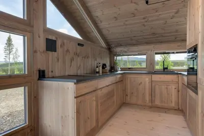 a kitchen with wooden cabinets and windows in a cabin at Hedda Robølshøvda - 3 bedroom cabin with a lovely view in Heggenes
