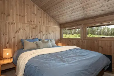 a bedroom with a bed in a wooden wall at Hedda Robølshøvda - 3 bedroom cabin with a lovely view in Heggenes