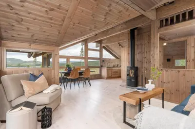 a living room with a couch and a table at Hedda Robølshøvda - 3 bedroom cabin with a lovely view in Heggenes
