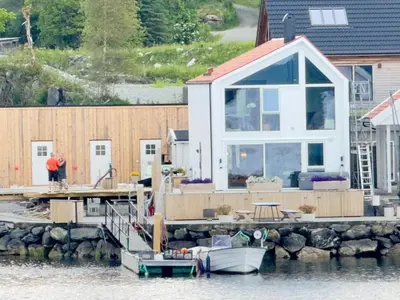 a house on a dock with a boat on the water at 6 person holiday home in Huglo in Nordhuglo