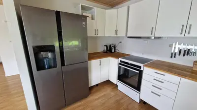 a kitchen with white cabinets and a stainless steel refrigerator at Seaside cabin with stunning view! in Ålesund