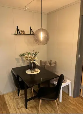a dining room table with black chairs and a lamp at Hafjell Alpinlandsby in Hafjell
