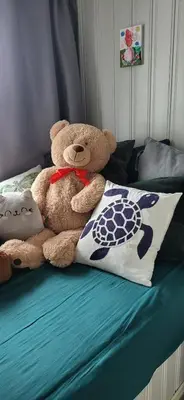 a teddy bear sitting on a bed with a pillow at Cottage in Hellesøy, Øygarden in Hellesøy