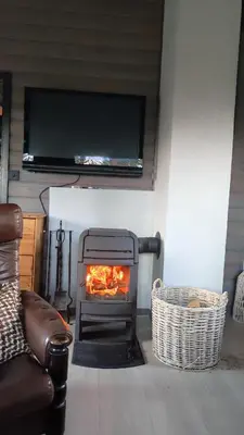 a living room with a fireplace with a tv above it at Mortenhytta, Valevåg in Valevåg