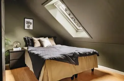 a bedroom with a bed in a attic with a window at Leilighet Bergen Sandviken in Bergen