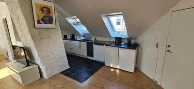 a kitchen with white cabinets and a black counter top at Leilighet Bergen Sandviken in Bergen