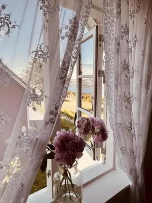 a window with flowers in a vase on a window sill at Cozy older house in scenic surroundings in Stord