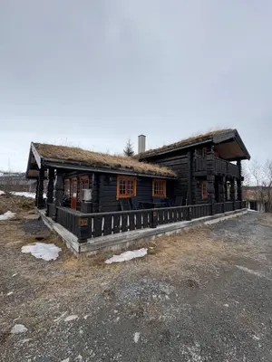 a wooden building with a roof on a field at Lomtjern in Beitostøl