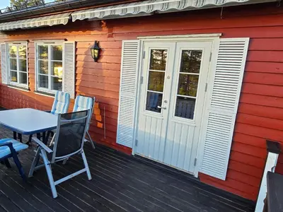 a table and chairs on a deck next to a red house at 6 person holiday home in Osen