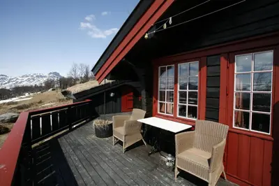 a deck with chairs and a table on a house at Stor tømmerhytte med fjellutsikt in Beitostøl