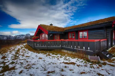 a house with a grass roof on a snow covered yard at Stor tømmerhytte med fjellutsikt in Beitostøl