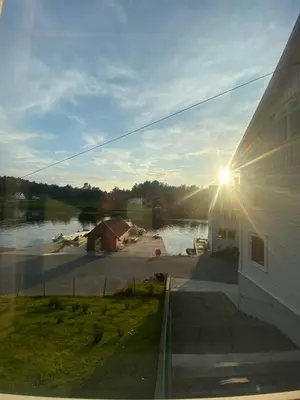 a view of the sun setting behind a building at Haraldseidvågen gjestgjevarstad in Skjold
