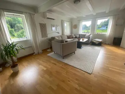 a living room with a couch and chairs and windows at Haraldseidvågen gjestgjevarstad in Skjold