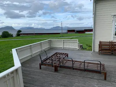two benches sitting on the deck of a house at Flø Feriehus med Badstue in Ulstein