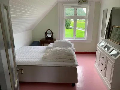 a bedroom with a bed with white sheets and a window at Flø Feriehus med Badstue in Ulstein
