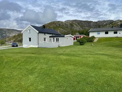 a large yard with two houses and a green field at Flott feriehus ved sjøen