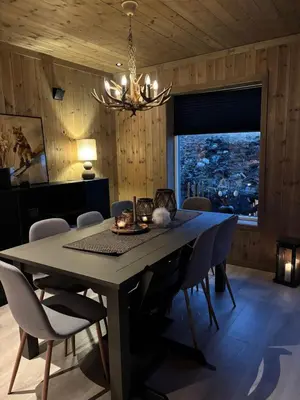 a dining room with a table and chairs and a chandelier at Ski inn ski out, downhill and crosscountry Holtardalen in Torvetjørn