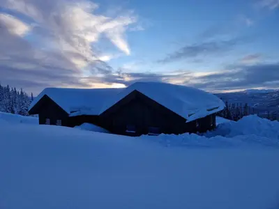 a building covered in snow with snow on the roof at Ny hytte med panoramautsikt in Hjartdal