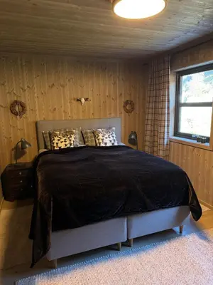 a bedroom with a bed with a black comforter and a window at Ny hytte med panoramautsikt in Hjartdal