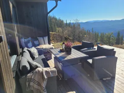a patio with a couch and a table on a deck at Ny hytte med panoramautsikt in Hjartdal