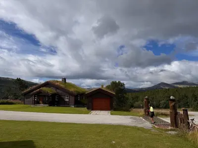 a person standing in front of a house with a grass roof at Høvringen Lodge in Høvringen