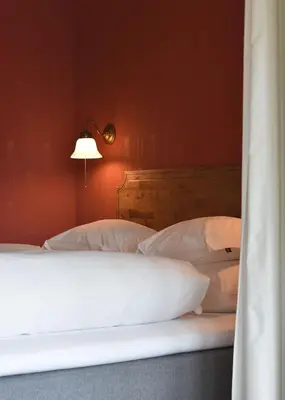 a bed with white pillows and a lamp in a room at Steien Hotel in Alvdal